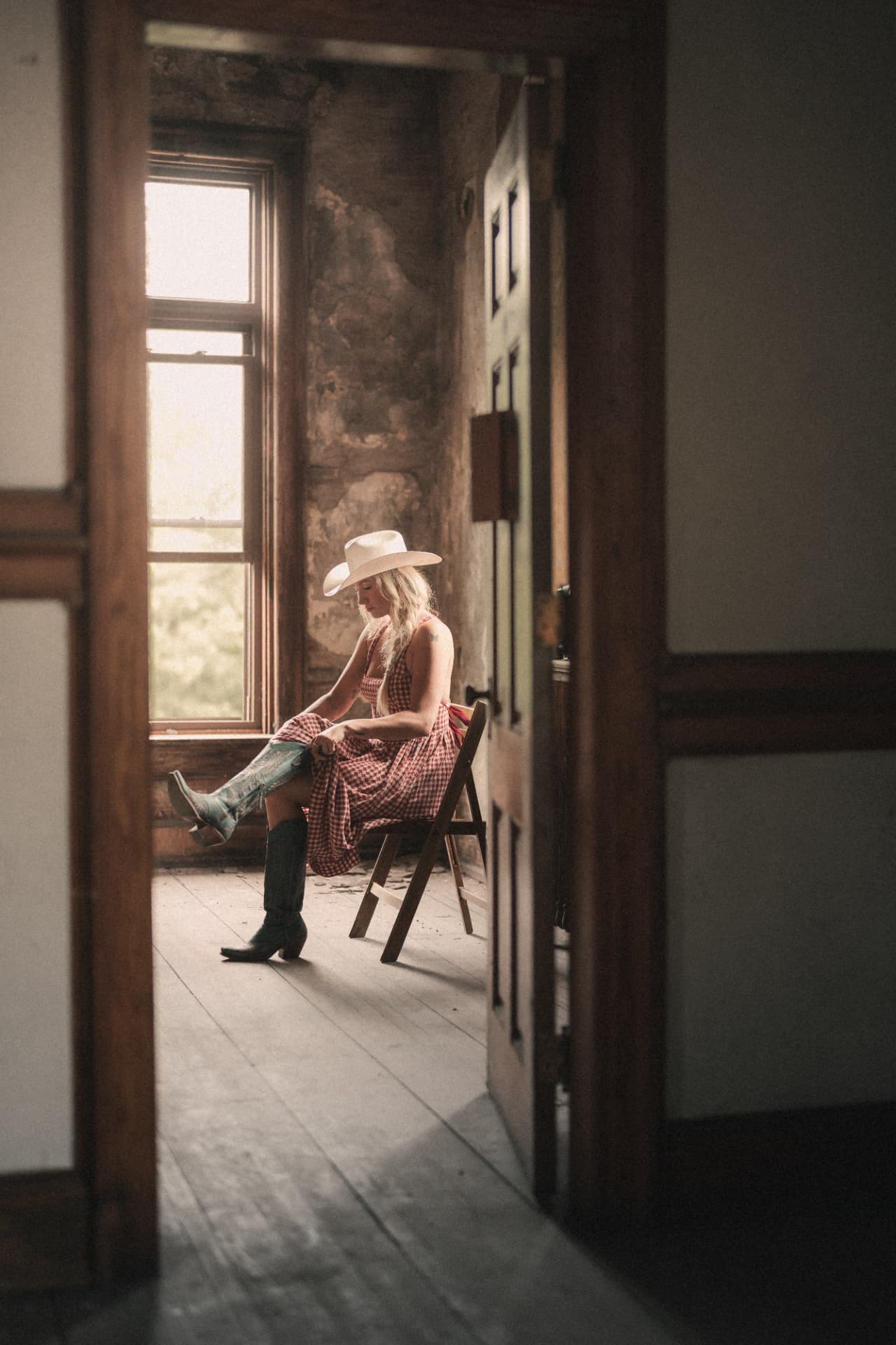 Diner seen through an open doorway, seated by a window pulling on a tall cowboy boot